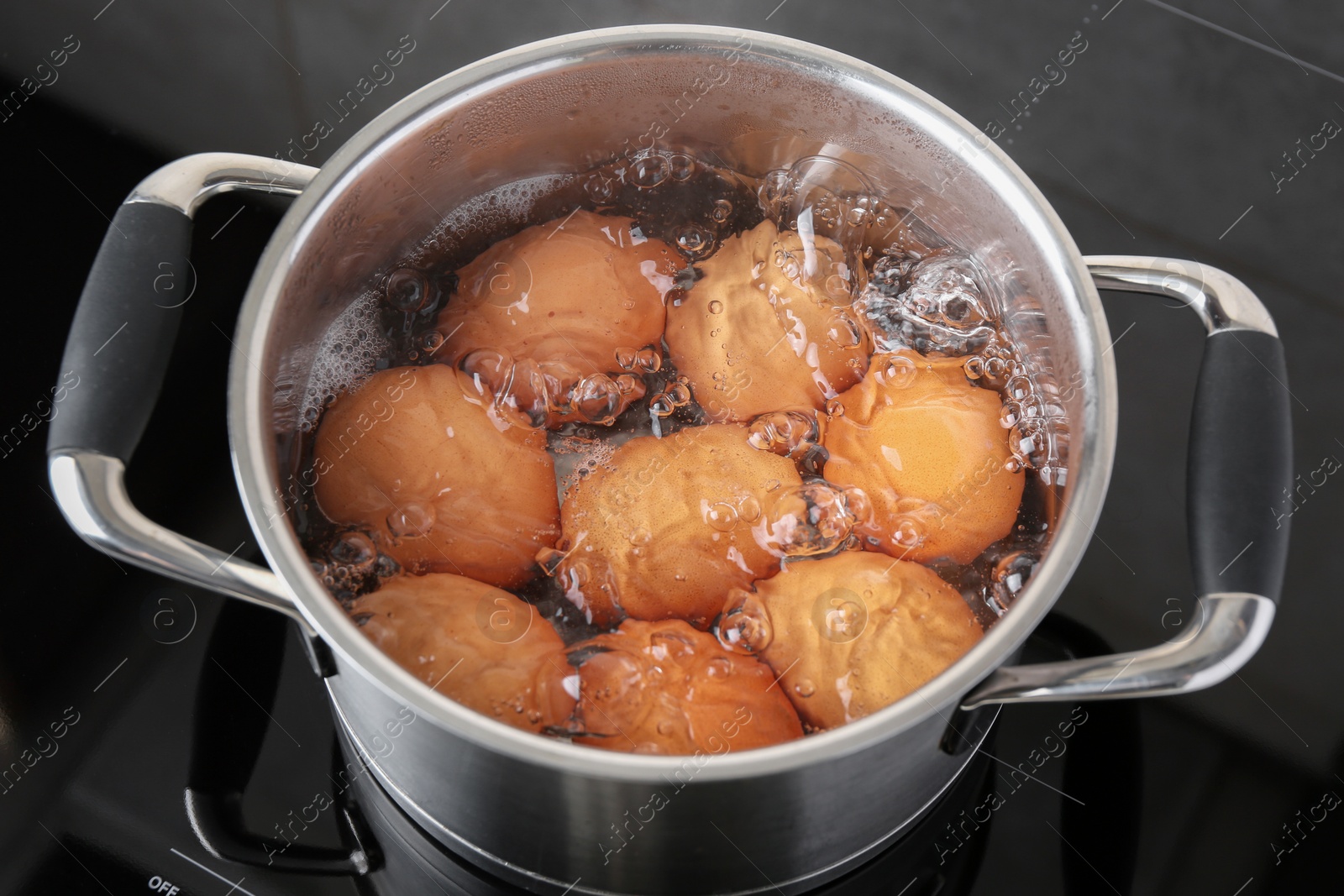 Photo of Chicken eggs boiling in pot on electric stove, above view