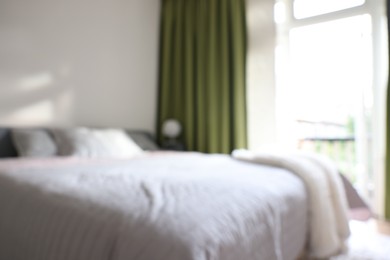 Photo of Blurred view of large bed near window in room