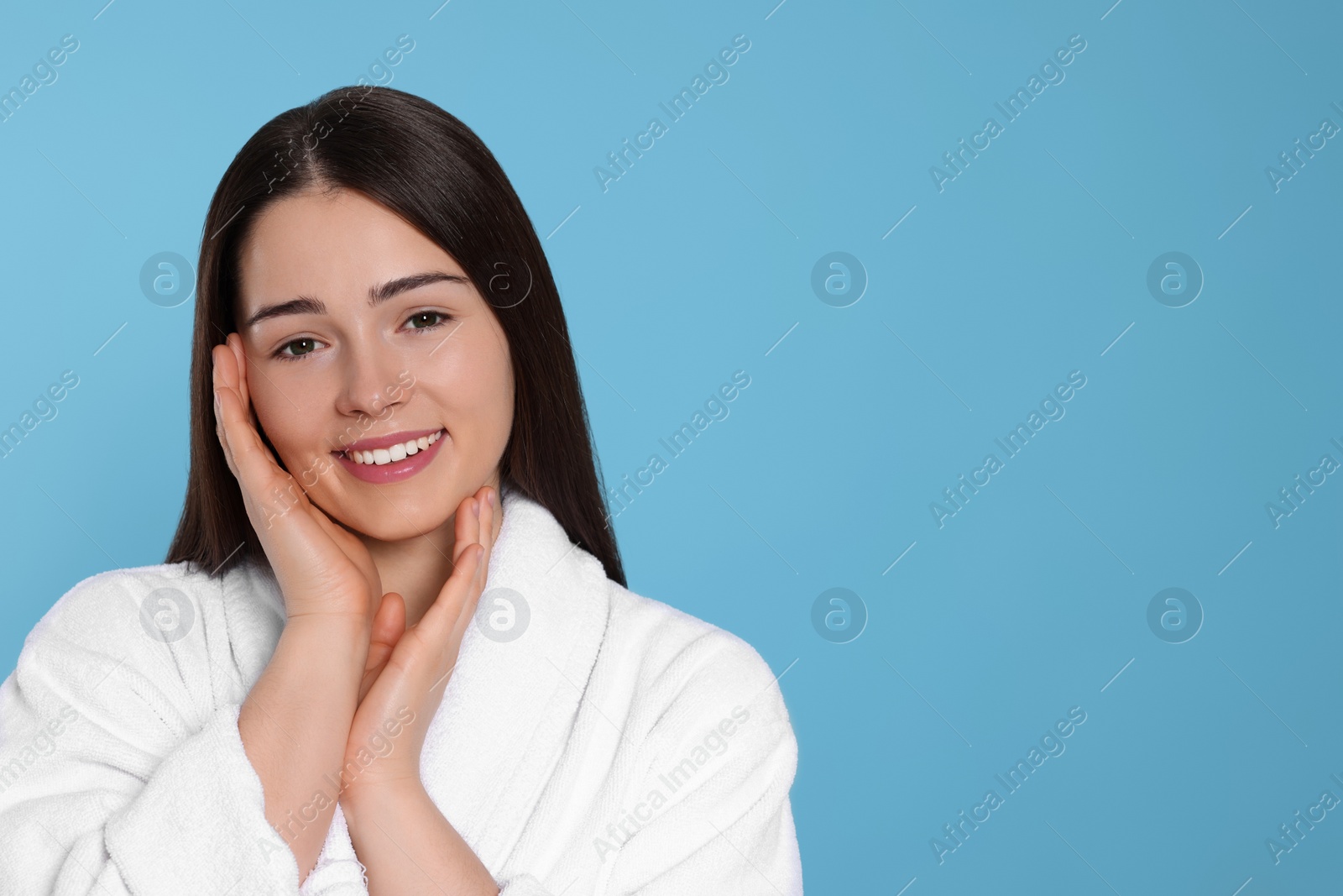 Photo of Portrait of attractive young woman in bathrobe on light blue background, space for text. Spa treatment