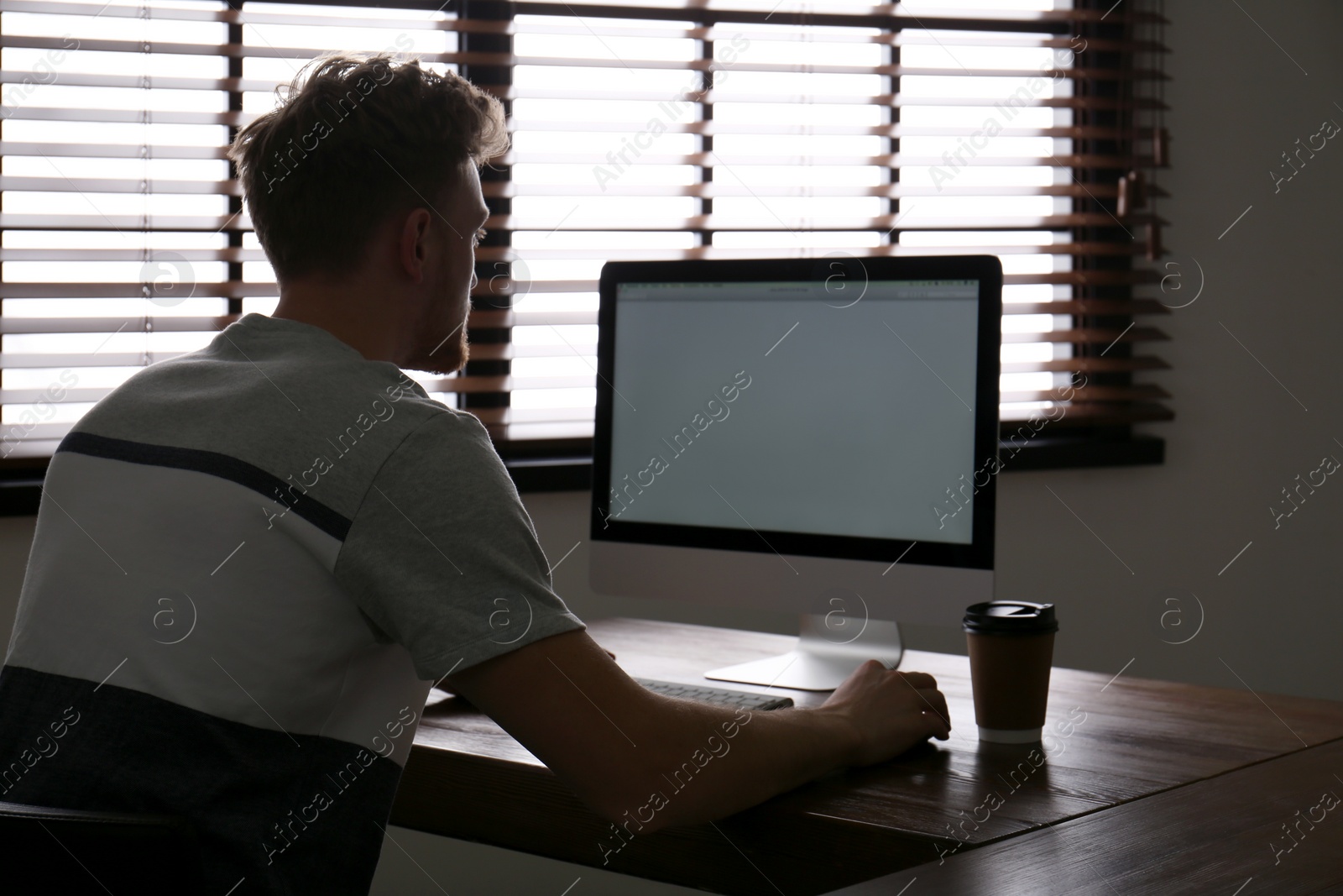 Photo of Lonely man sitting at computer with empty screen indoors