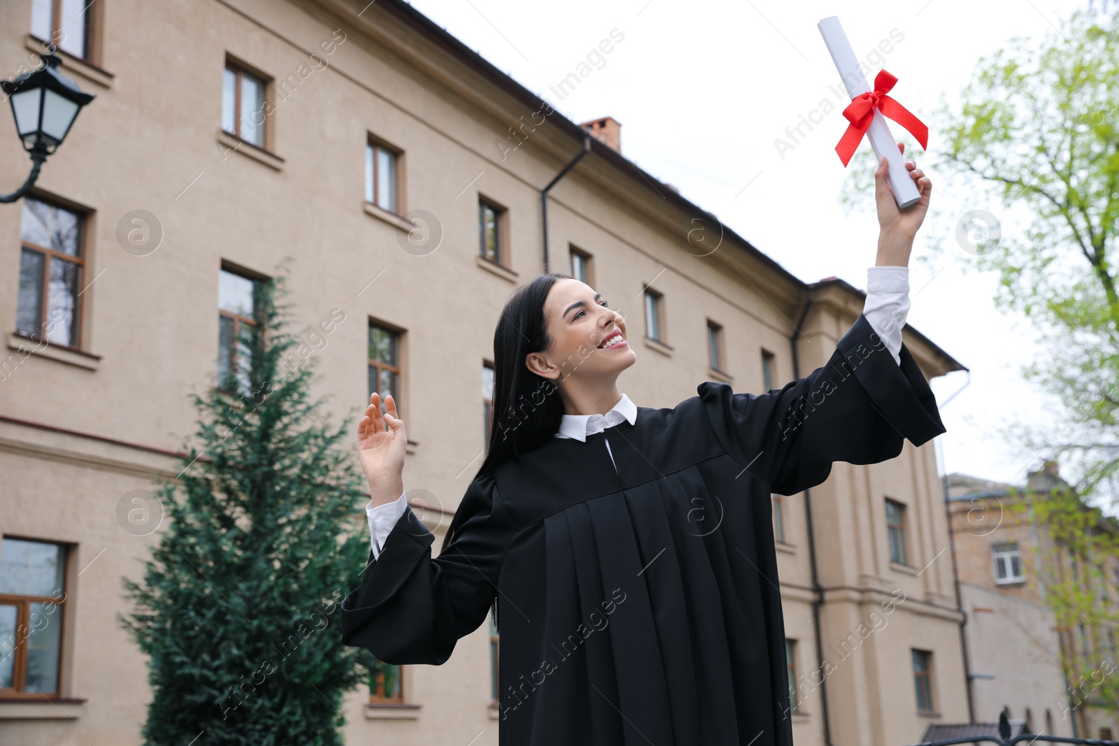 Photo of Happy student with diploma after graduation ceremony outdoors