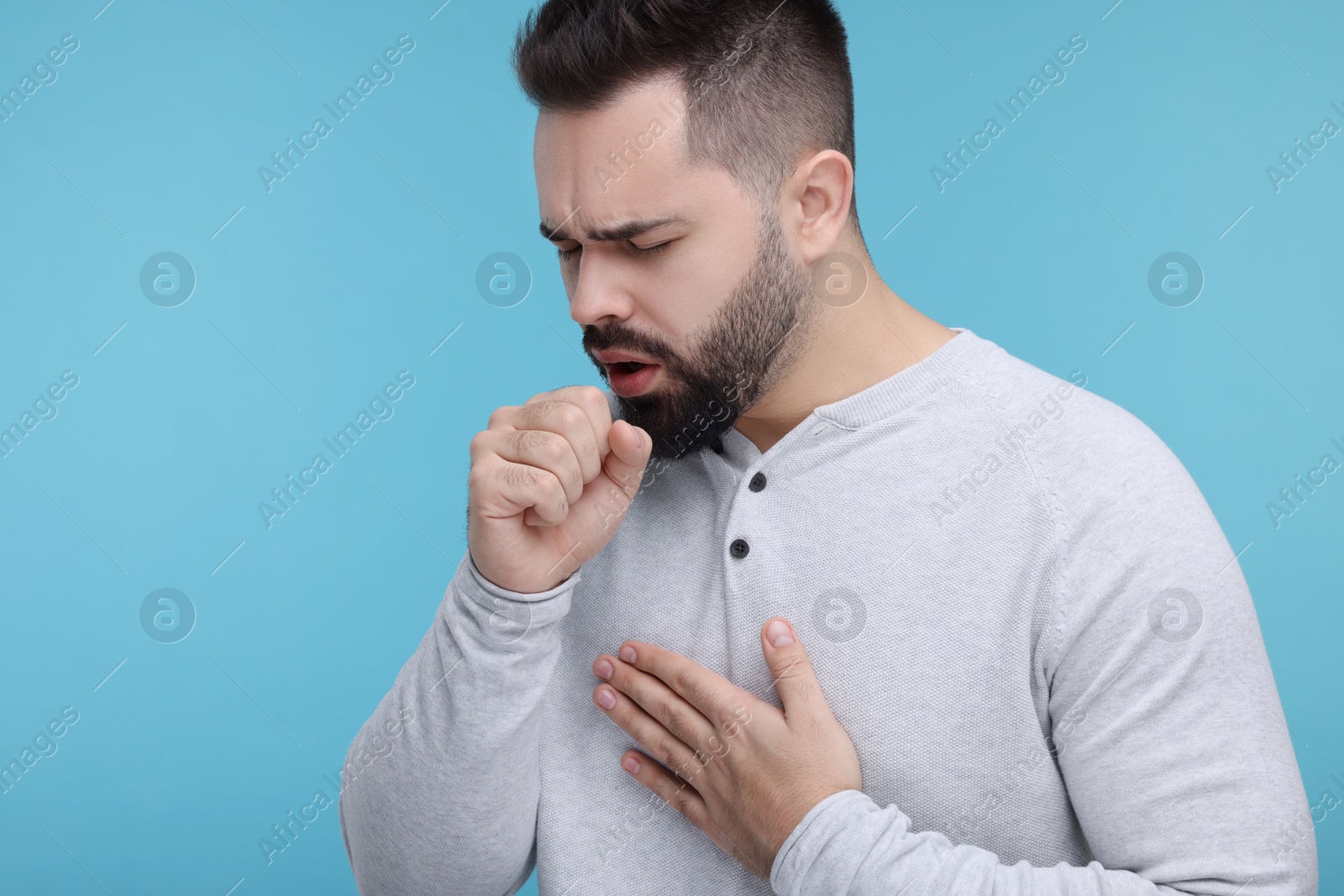 Photo of Sick man coughing on light blue background