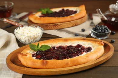 Photo of Delicious sweet cottage cheese pastry with cherry jam on wooden table