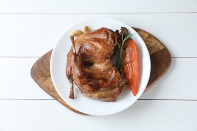 Photo of Tasty cooked rabbit meat with rosemary, garlic and carrot on white wooden table, top view