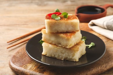 Photo of Delicious turnip cake with microgreens served on wooden table, closeup