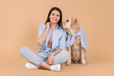 Happy woman with cute Labrador Retriever on beige background