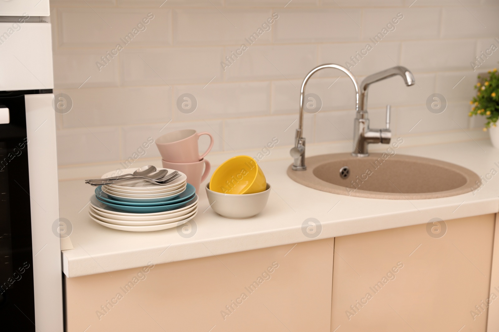 Photo of Clean dishware and cutlery on counter near kitchen sink