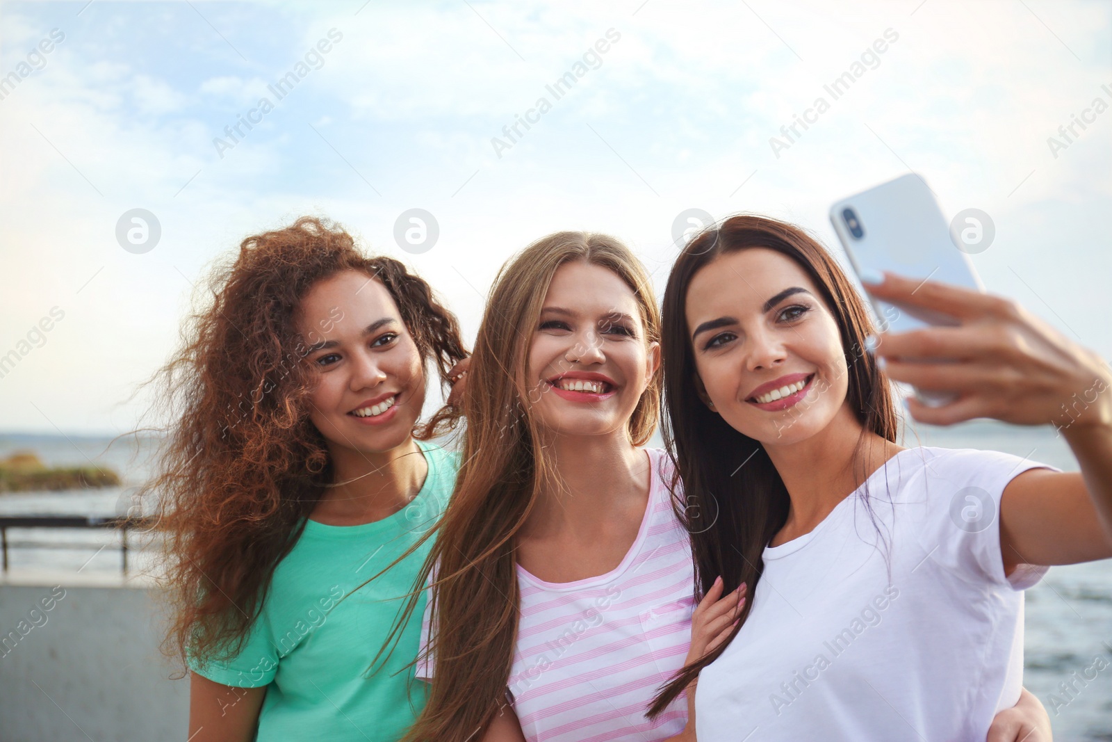 Photo of Happy young women taking selfie outdoors on sunny day