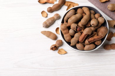 Photo of Delicious ripe tamarinds on white wooden table, flat lay. Space for text