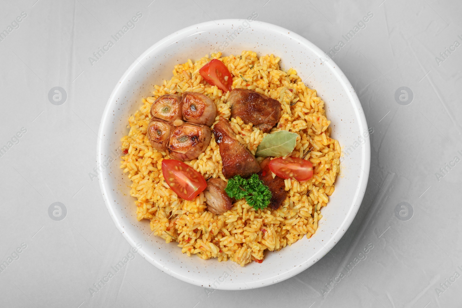 Photo of Bowl with delicious rice pilaf on grey background, top view