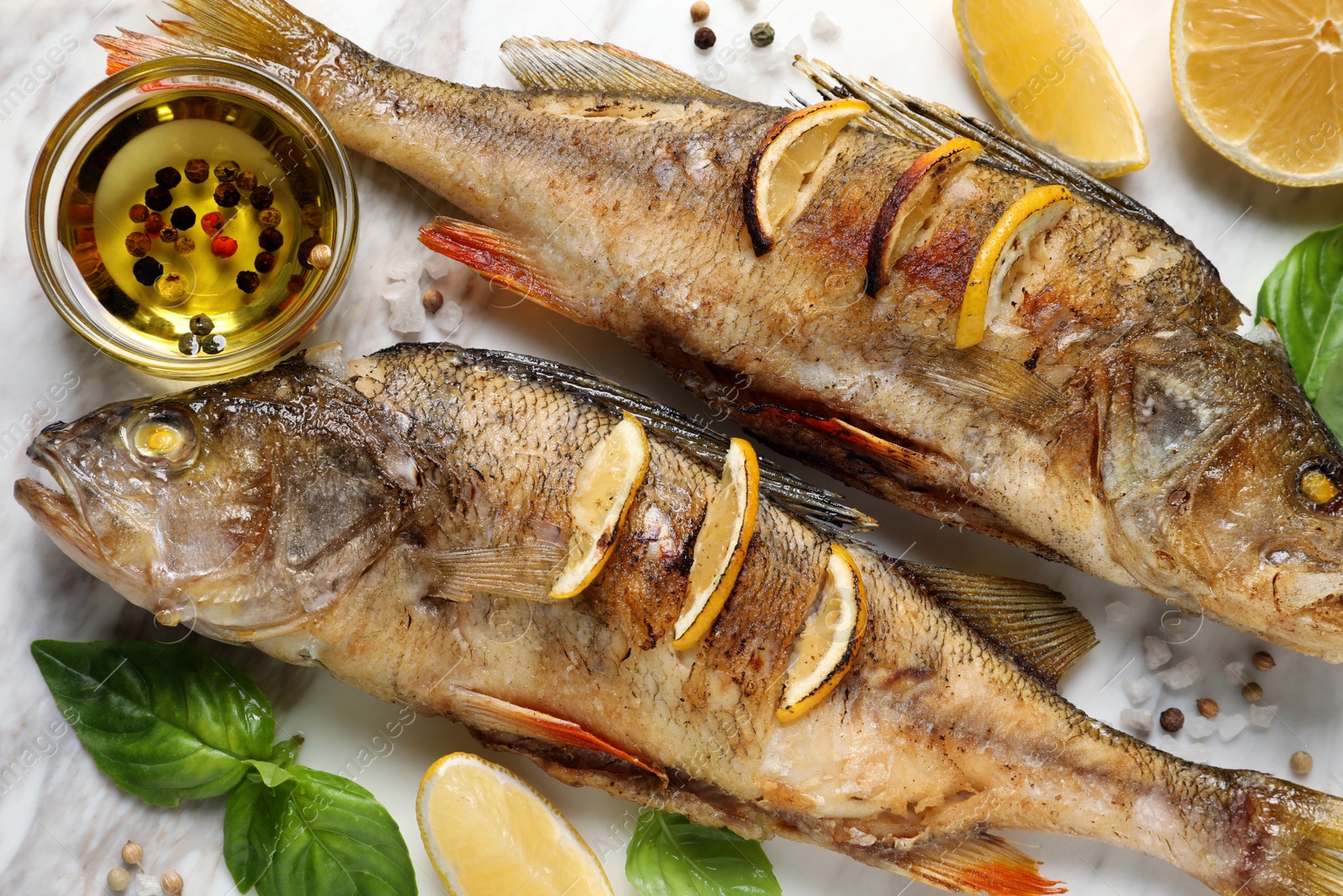 Photo of Tasty homemade roasted perches served on white board, flat lay. River fish