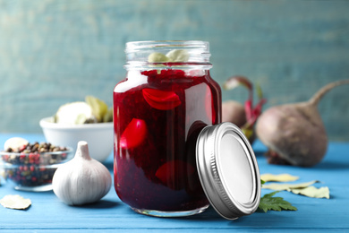 Photo of Pickled beets in glass jar on light blue wooden table