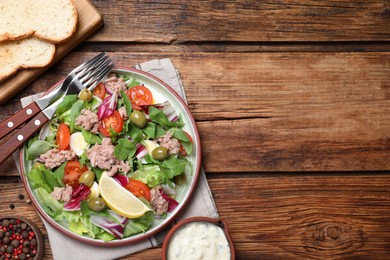 Photo of Plate of delicious salad with canned tuna and vegetables served on wooden table, flat lay. Space for text