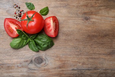 Fresh green basil leaves, spices with cut and whole 
tomatoes on wooden table, flat lay. Space for text