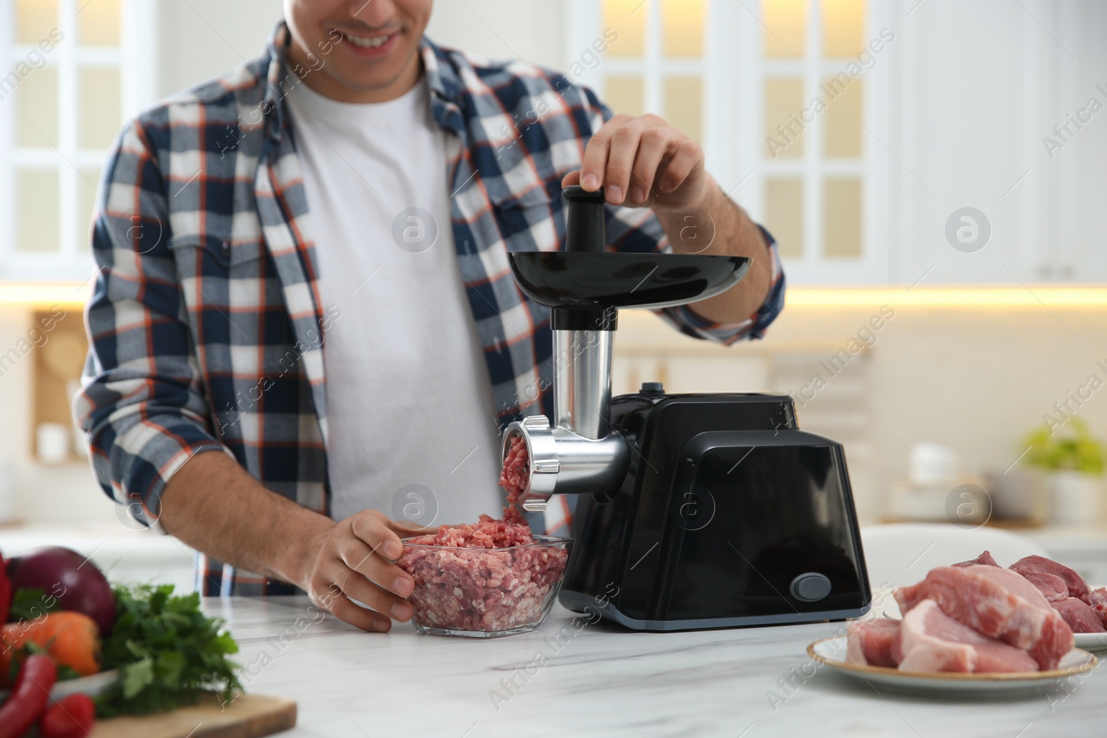 Photo of Man using modern meat grinder in kitchen, closeup