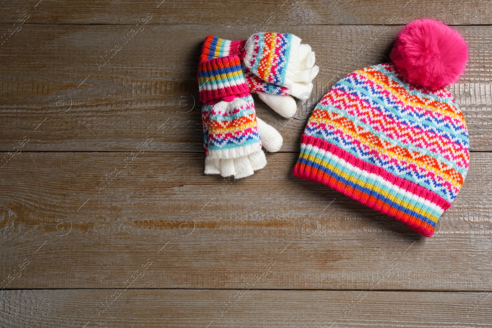 Photo of Warm knitted hat and mittens on wooden background, flat lay. Space for text
