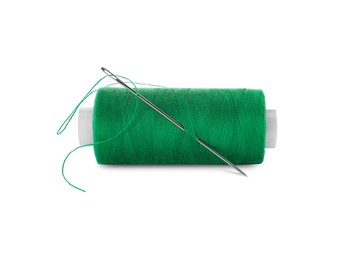 Photo of Spool of green sewing thread with needle isolated on white