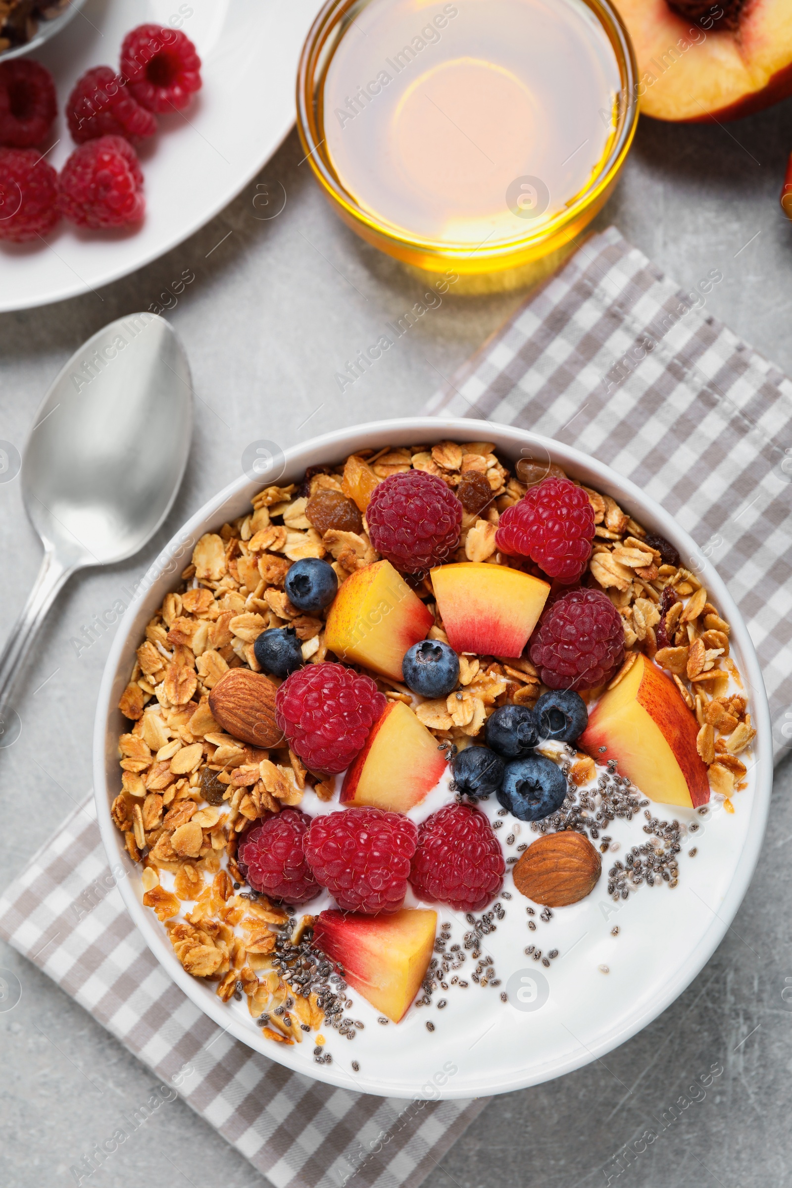 Photo of Tasty homemade granola with yogurt served on grey table, flat lay. Healthy breakfast