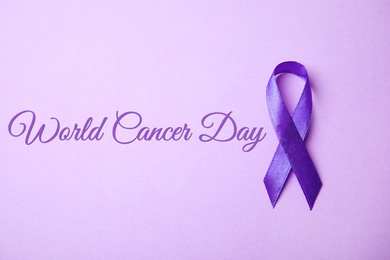 Purple ribbon on lilac background, top view. World Cancer Day