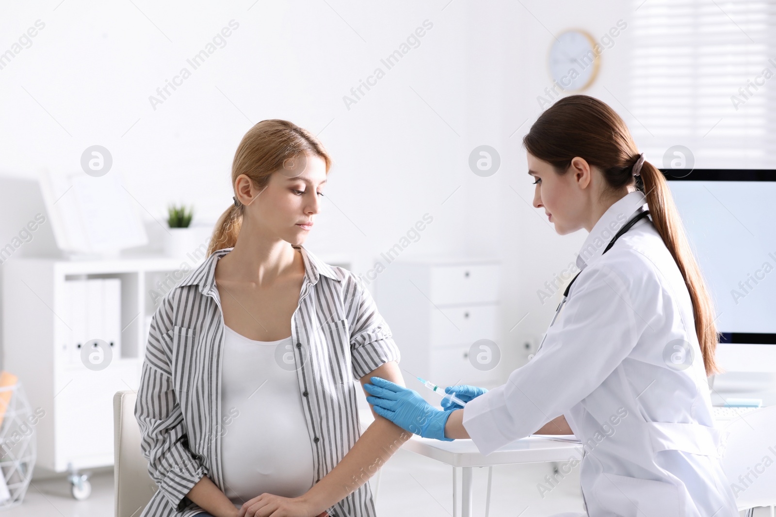 Photo of Doctor giving injection to pregnant woman in hospital. Vaccination concept
