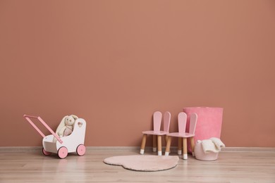 Child's toys and chairs near pink wall indoors. Interior design