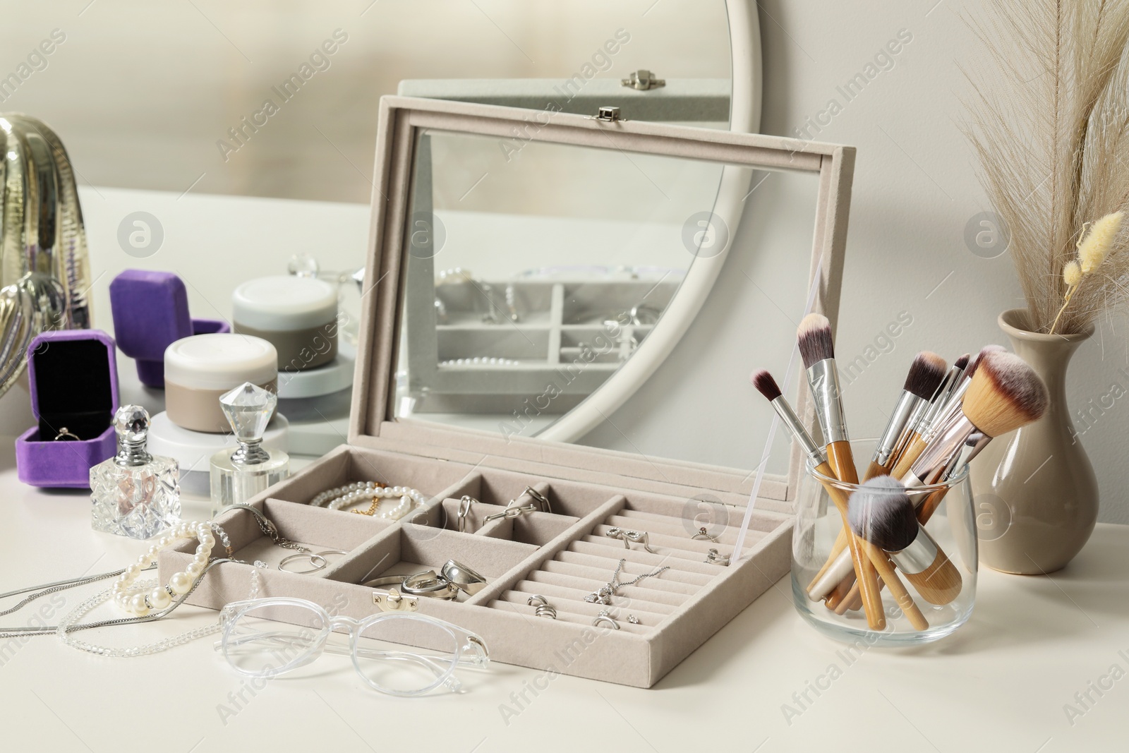 Photo of Jewelry box with many different accessories, perfumes and decor on white table