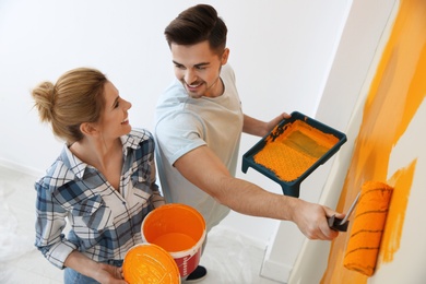 Photo of Happy couple painting wall indoors, above view. Home repair