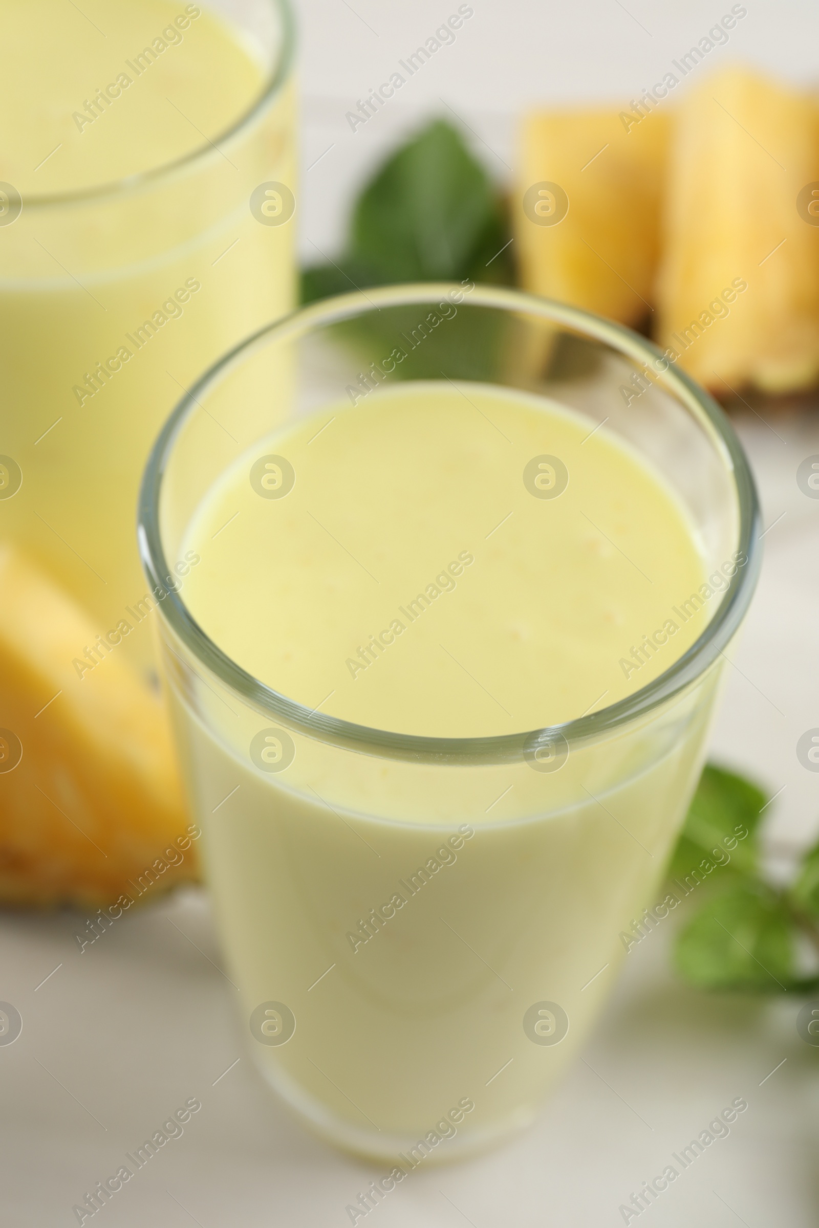 Tasty pineapple smoothie on white table, closeup Photo of Tasty pineapple smoothie on white table, closeup