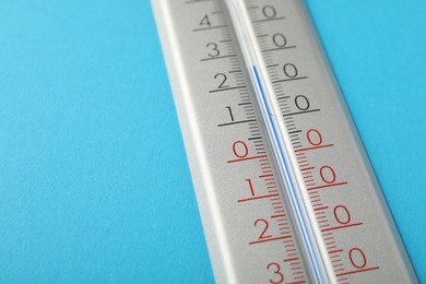 Photo of Weather thermometer on light blue background, closeup. Space for text