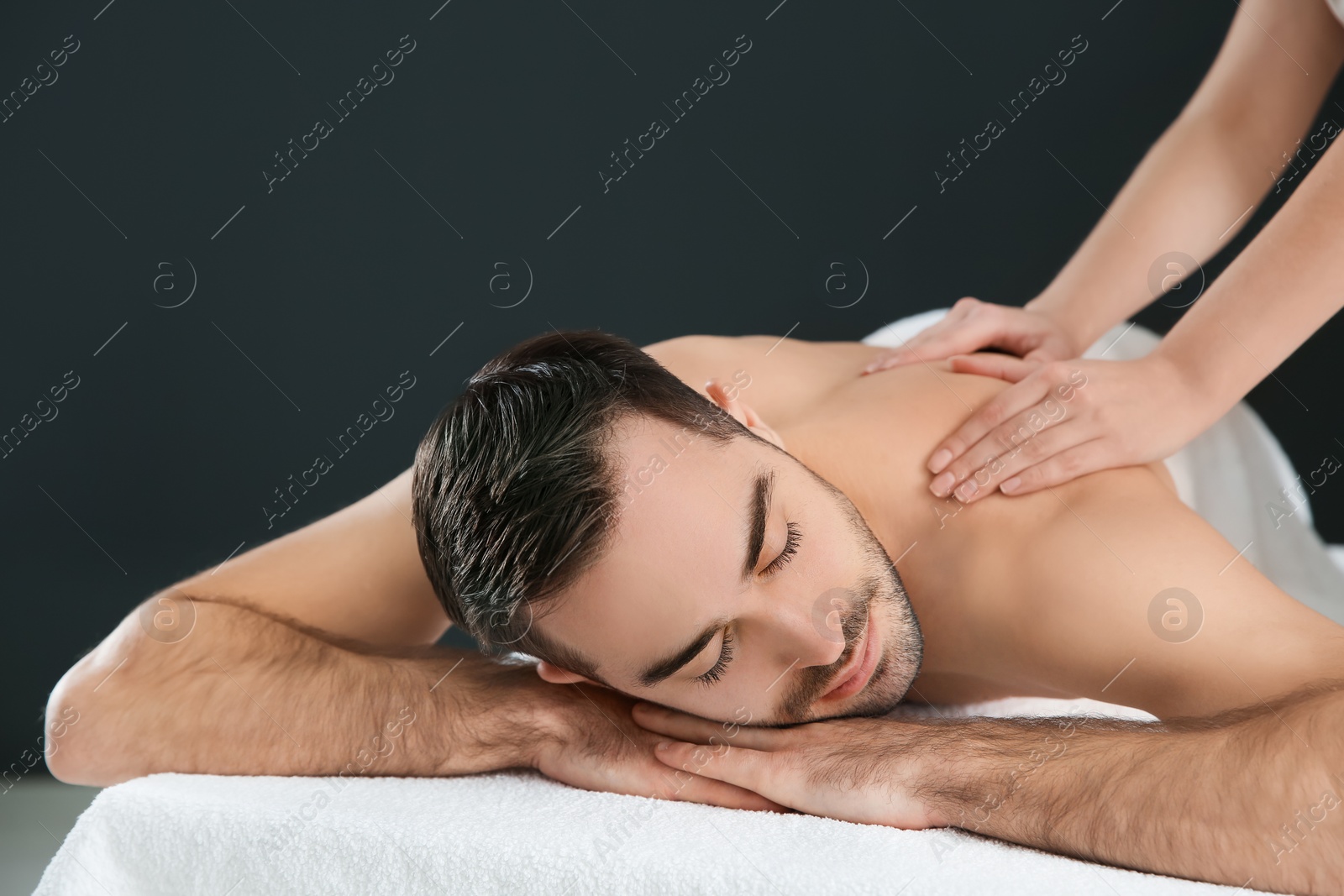 Photo of Handsome man receiving back massage on black background. Spa service