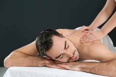 Photo of Handsome man receiving back massage on black background. Spa service
