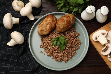 Photo of Tasty buckwheat with parsley and cutlets on wooden table, flat lay