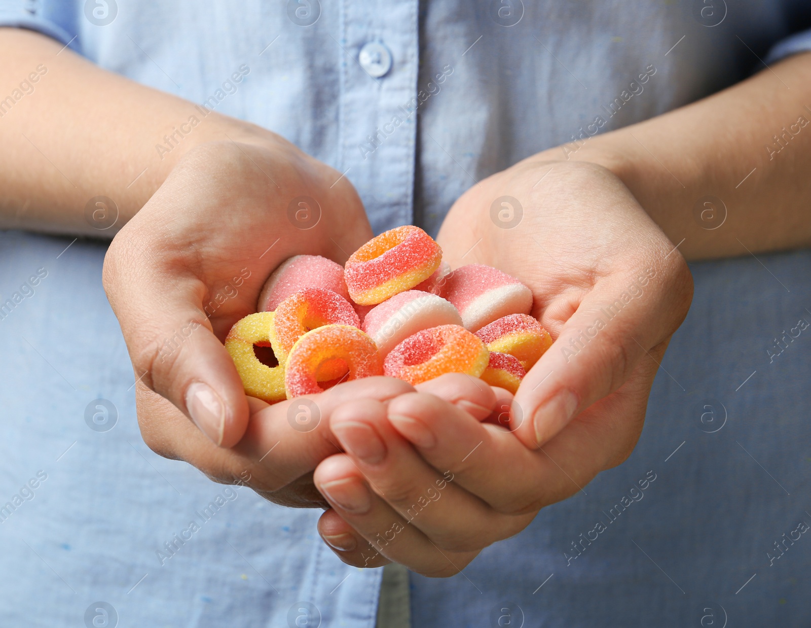 Photo of Young woman holding handful of tasty jelly candies, closeup