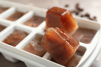 Photo of Ice cube tray with frozen coffee on table, closeup