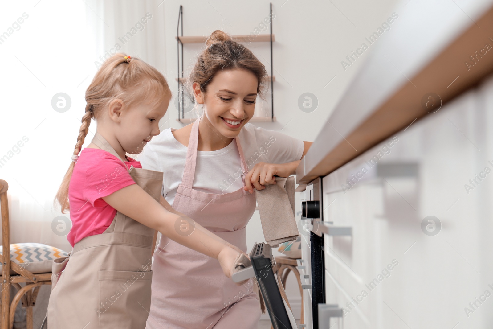 Photo of Mother and her daughter baking food in oven at home