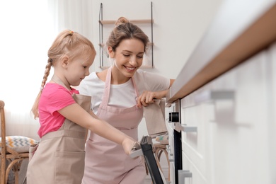 Mother and her daughter baking food in oven at home