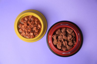 Wet pet food in feeding bowls on violet background, flat lay