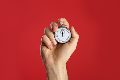 Photo of Man holding vintage timer on red background, closeup
