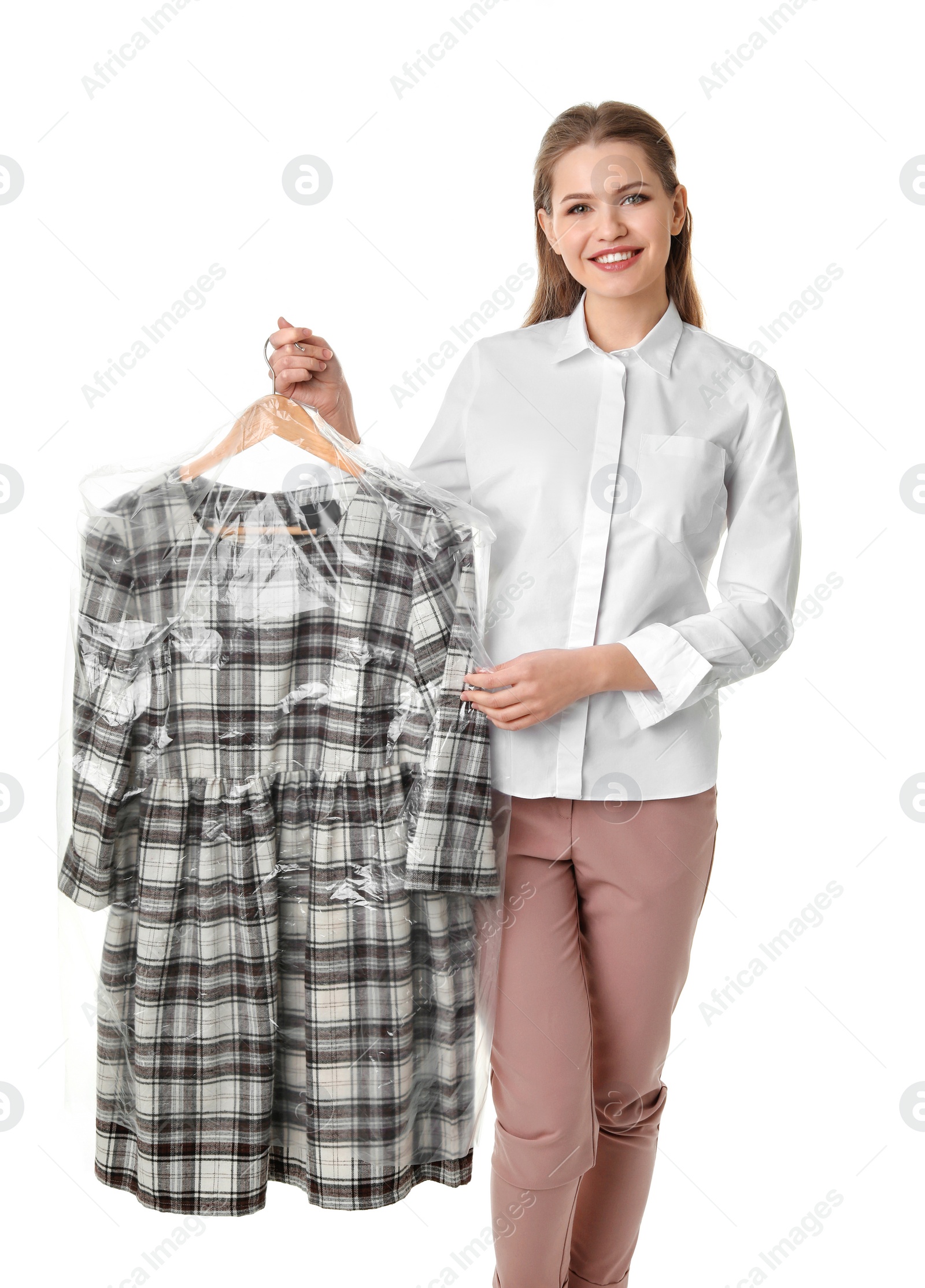 Photo of Young woman holding hanger with dress in plastic bag on white background. Dry-cleaning service