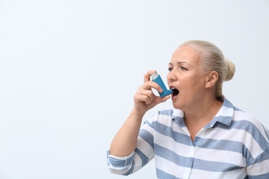 Photo of Woman using asthma inhaler on white background