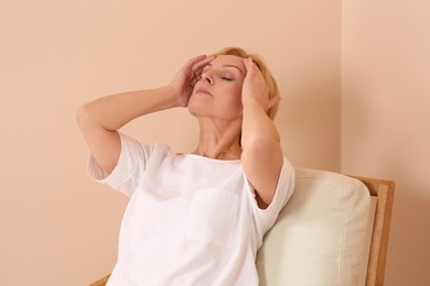 Photo of Woman suffering from headache near beige wall indoors. Hormonal disorders