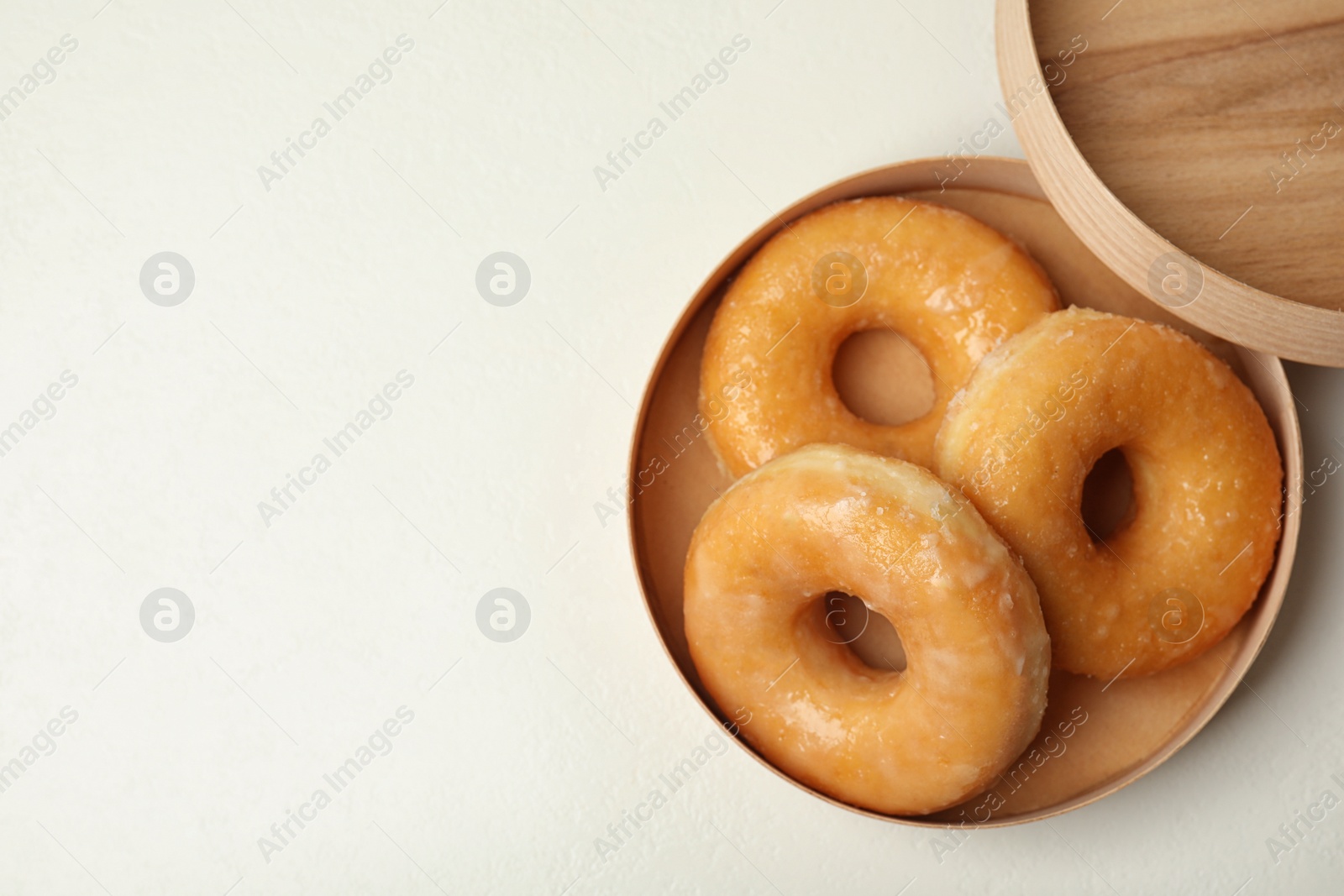 Photo of Delicious donuts on white table, top view. Space for text