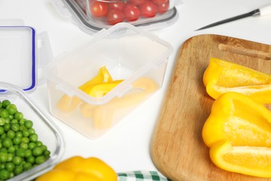 Photo of Containers with cut bell pepper and fresh products on white table. Food storage