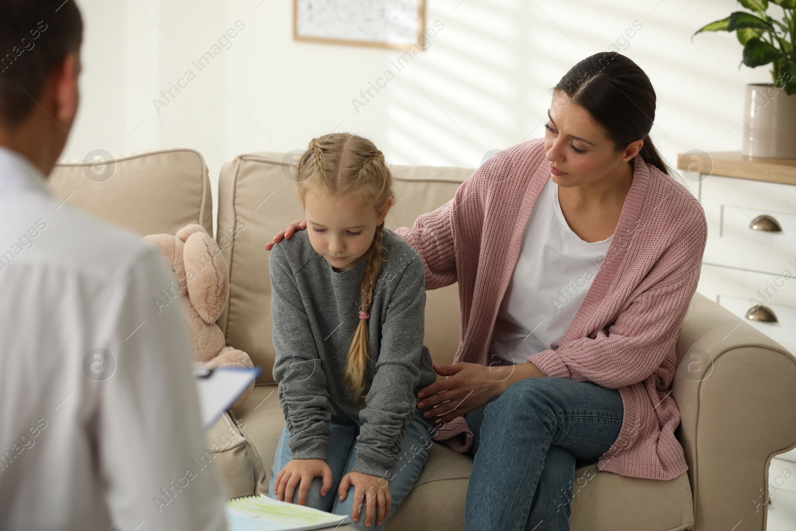 Photo of Little girl and her mother on appointment with child psychotherapist indoors