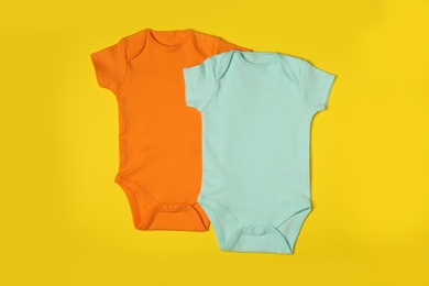 Photo of Cute baby onesies on color background, top view