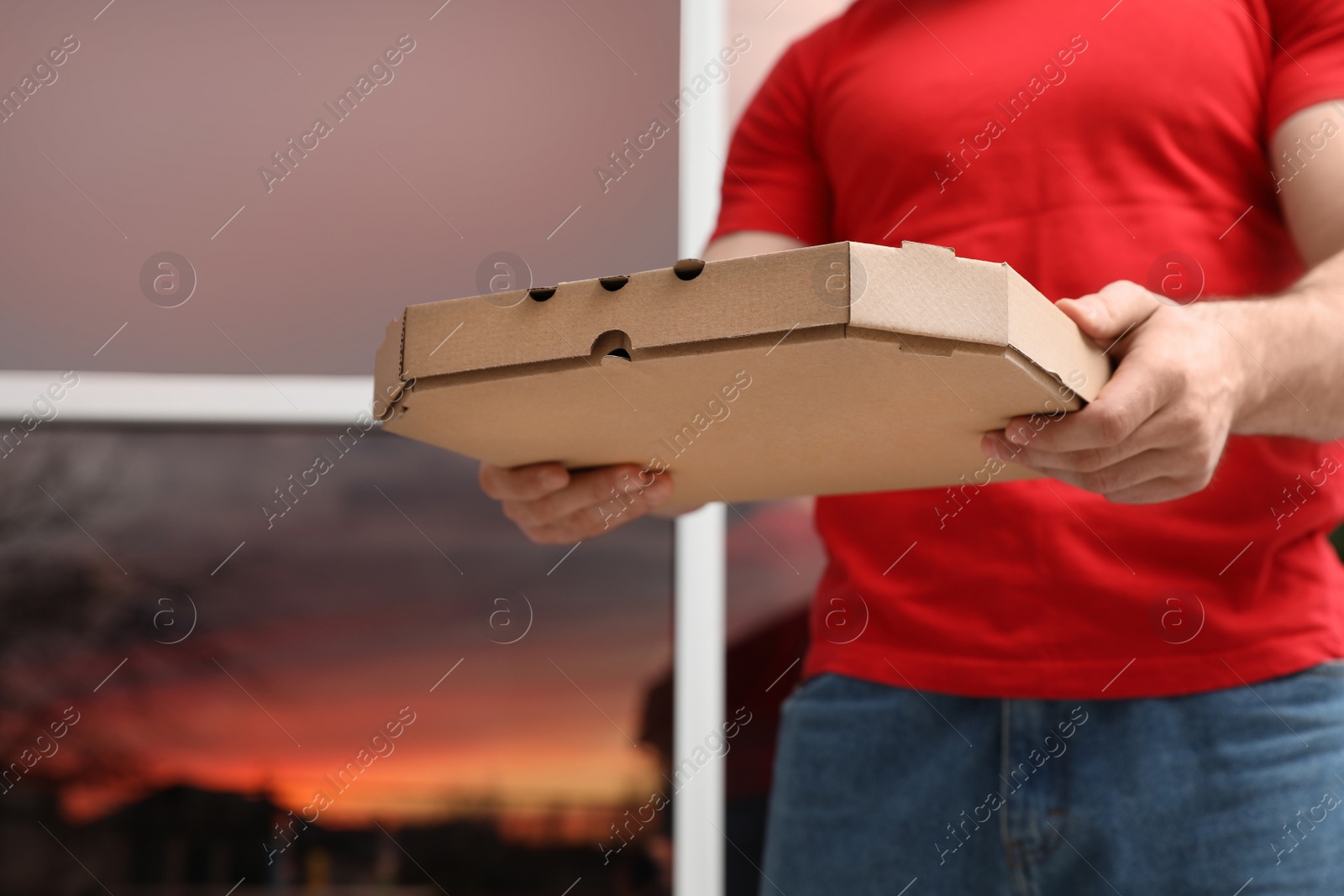 Photo of Courier with pizza box on blurred background, closeup