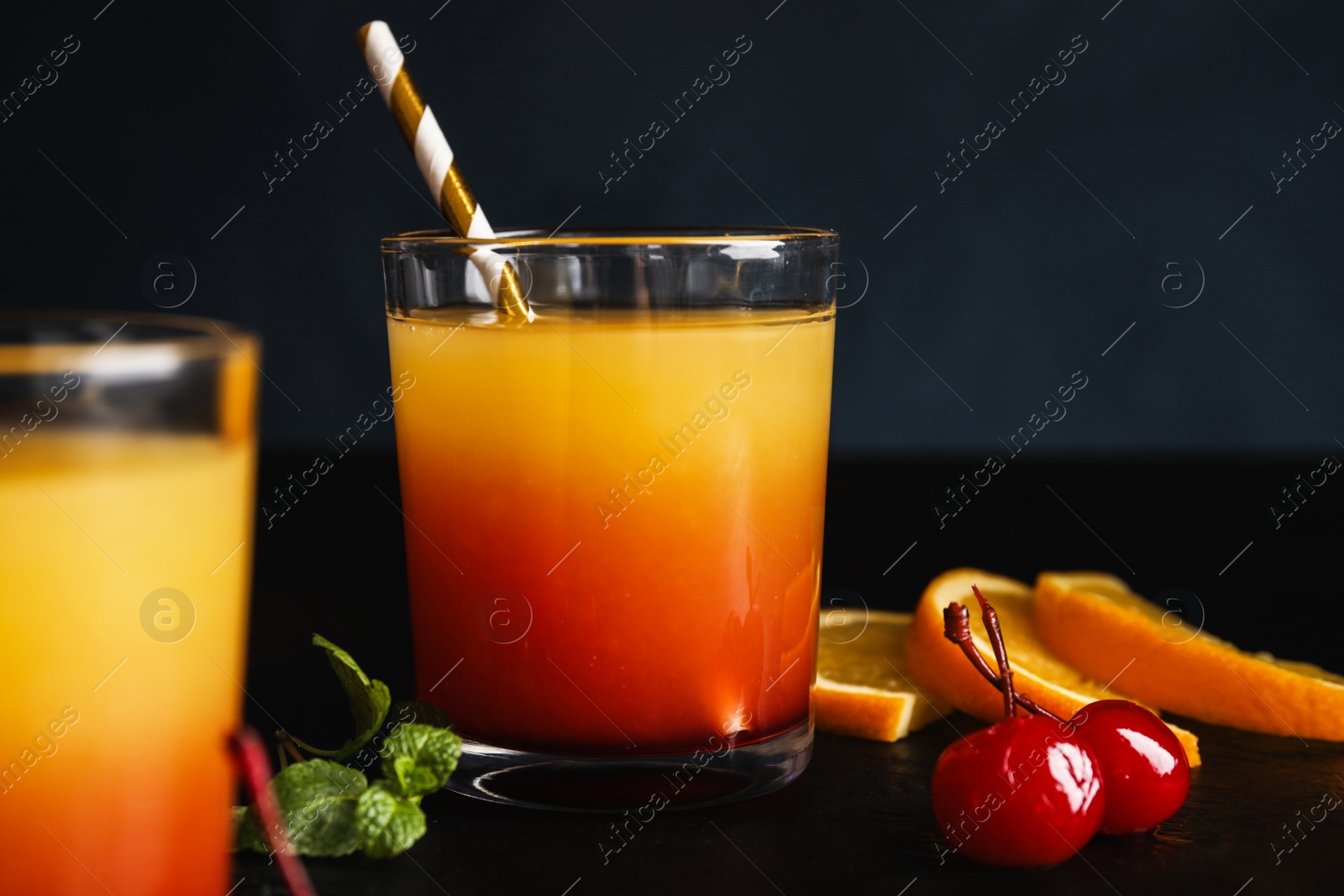 Photo of Fresh alcoholic Tequila Sunrise cocktail on black table