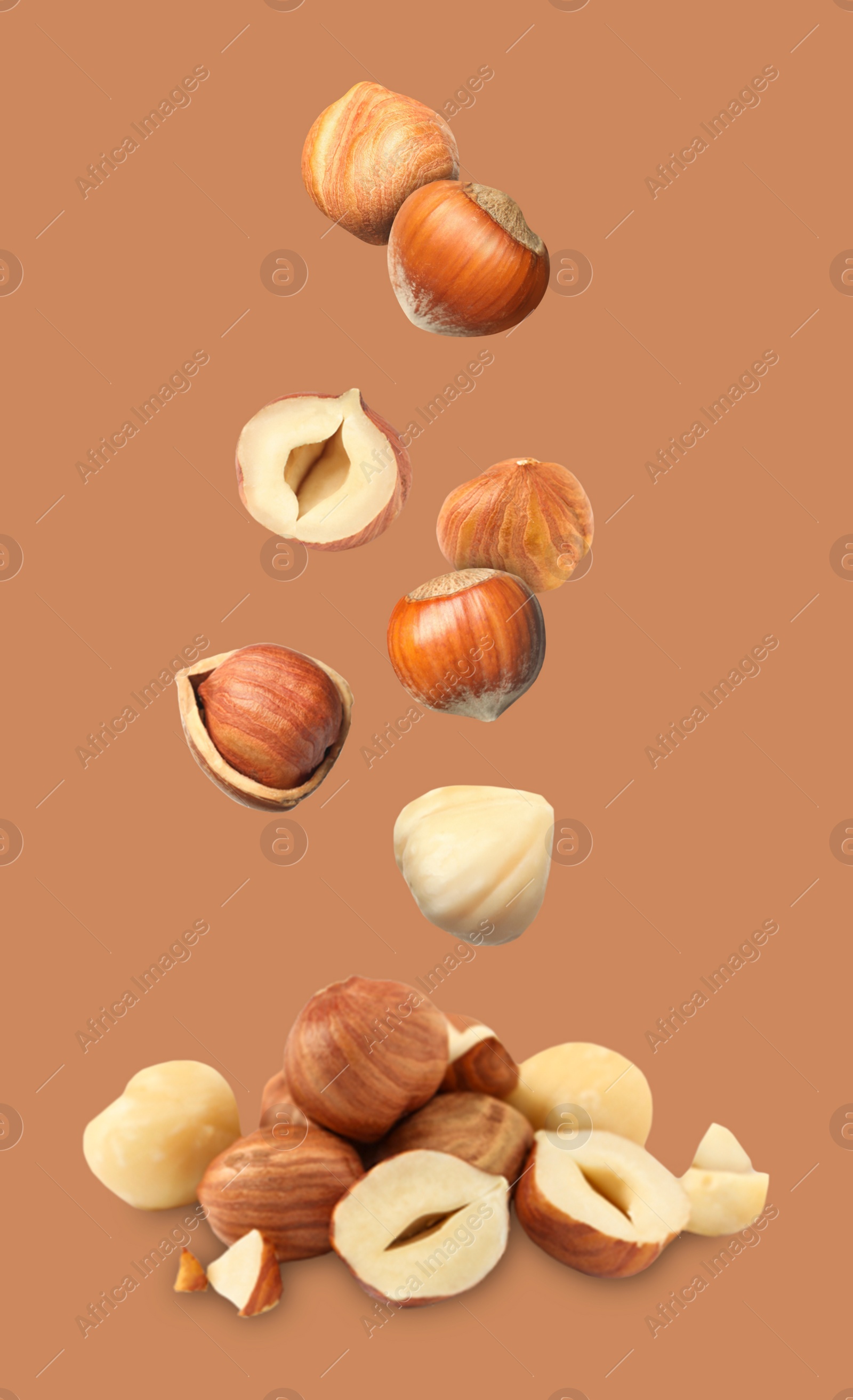 Image of Many fresh hazelnuts falling on light brown background