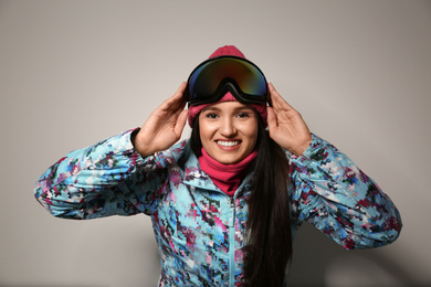 Woman wearing stylish winter sport clothes on light grey background