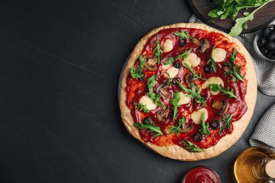 Pita pizza with cheese, olives, mushrooms and arugula on black table, flat lay. Space for text